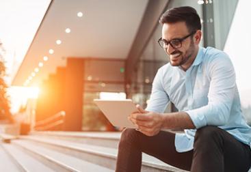 Man looking at tablet with sun on the horizon